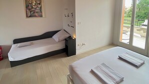 A bedroom with two beds, a wooden ceiling, a painting on the wall, and a window with a view. - A cozy and serene place for those seeking tranquility and comfort (Porpetto)