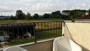 A balcony with two white plastic chairs and a beige table. - A cozy and serene place for those seeking tranquility and comfort (Porpetto)