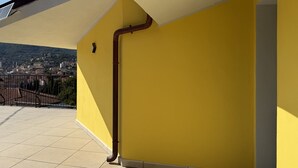 Un edificio amarillo con una tubería marrón visible y un piso de baldosas.