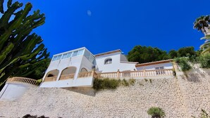 A white building with a stone facade, arched windows, and a balcony with a railing. - Villa 'Gaga Moraira' with Sea Views, Wi-Fi, and Air Conditioning (Teulada)