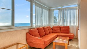A room with a large orange sofa, a wooden coffee table, and a view of the ocean through large windows. - Villa 'Gaga Moraira' with Sea Views, Wi-Fi, and Air Conditioning (Teulada)