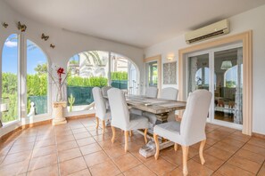 Een eethoek met een grote tafel, stoelen en uitzicht op groen.