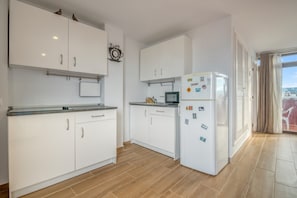 A modern kitchen with white cabinets, a refrigerator, and a clock on the wall. - Apartment 'Paraíso' with Sea View, Wi-Fi and Air Conditioning (Dénia)