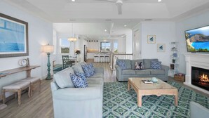 A spacious living room with a fireplace, a dining area, and a kitchen in the background. - Steps to Beach, Heated Pool, Elevator, Game Room (St. Augustine Beach)