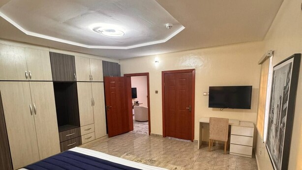 A bedroom with a bed, wardrobe, desk, and a television.