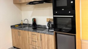 A kitchen with wooden cabinets, a black microwave, and a stainless steel refrigerator.