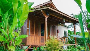 Una casa de madera con techo de tejas, rodeada de abundante vegetación.