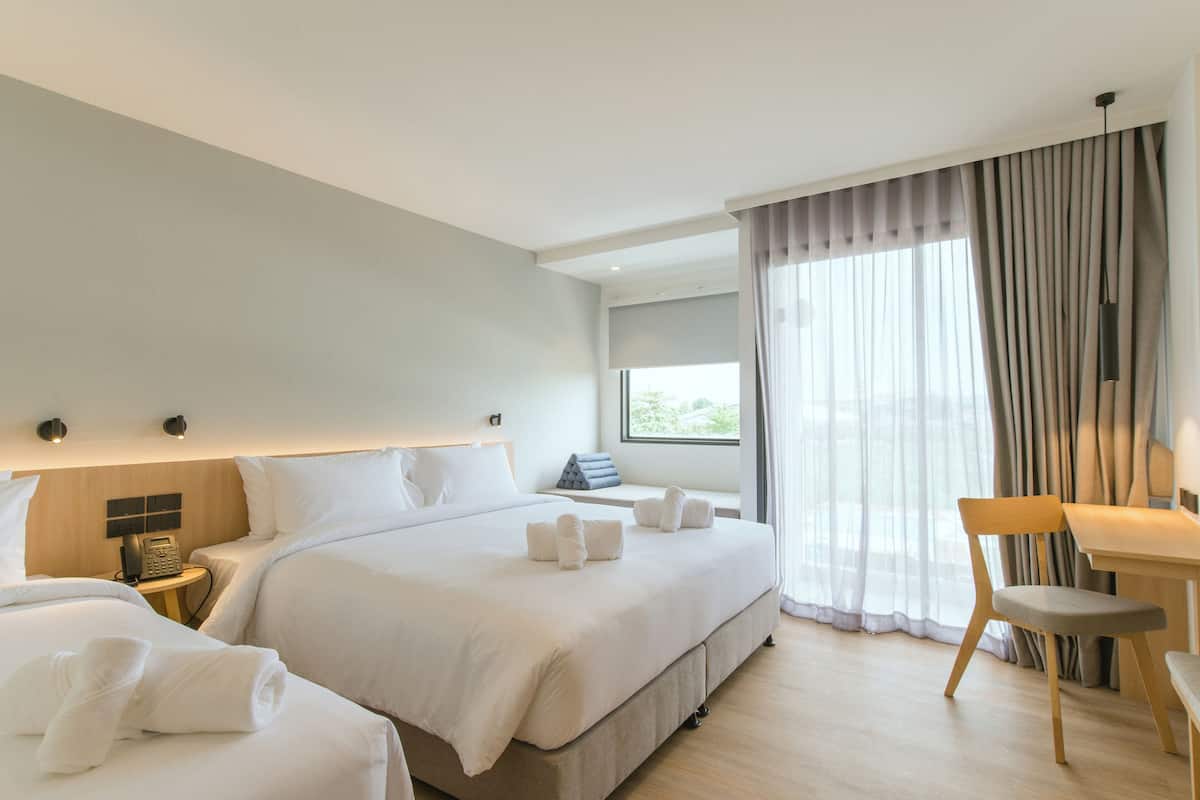 A hotel room with two beds, a desk, and a chair.
