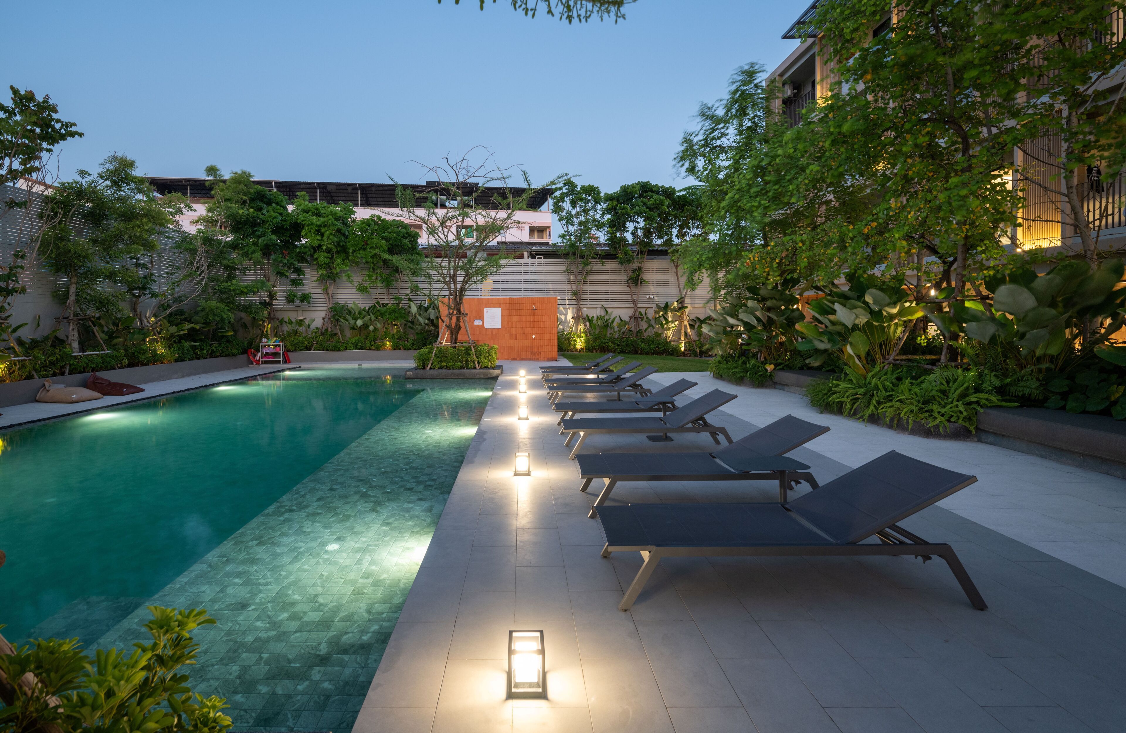 A swimming pool with lounge chairs and a wooden structure in the background.