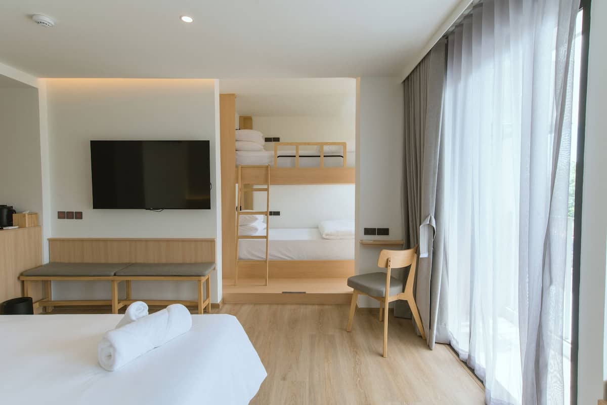 A modern hotel room with a bunk bed, a flat-screen TV, a desk, and a chair.