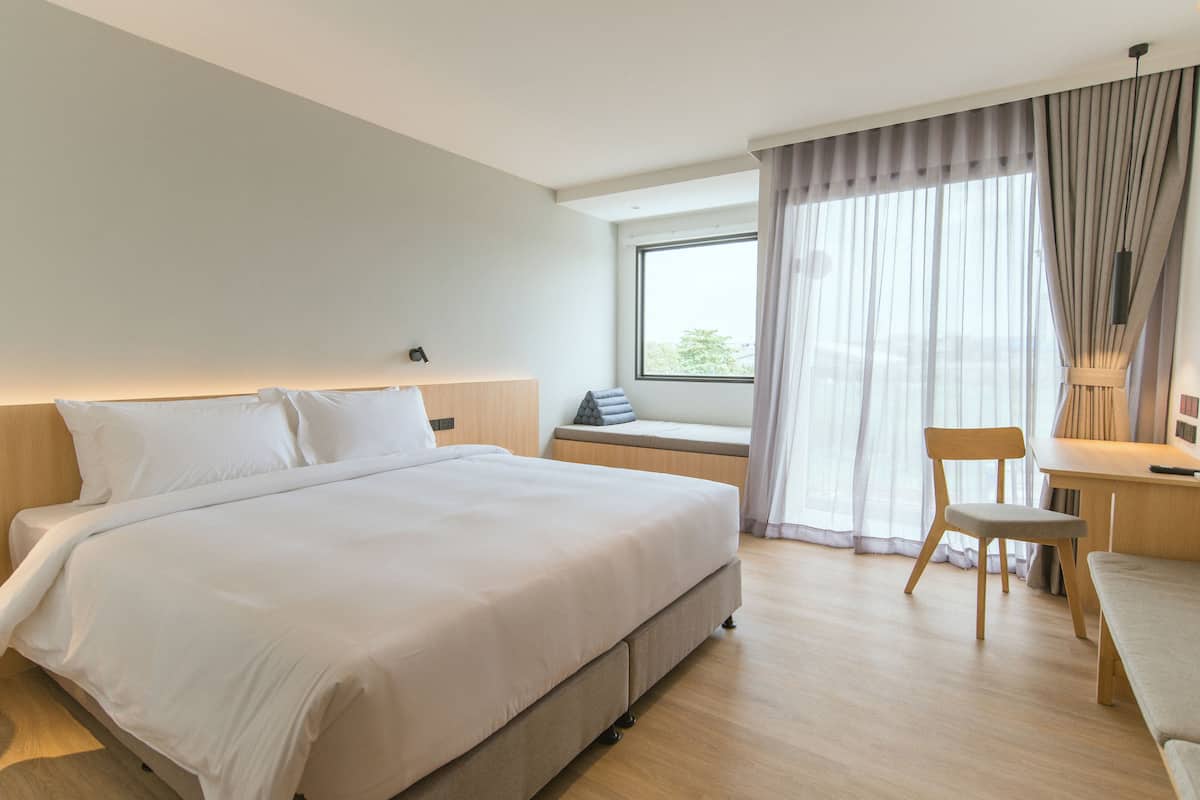 A modern hotel room with a large bed, a desk, and a chair.