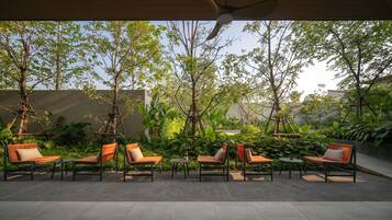 An outdoor seating area with chairs and tables, surrounded by trees and plants.