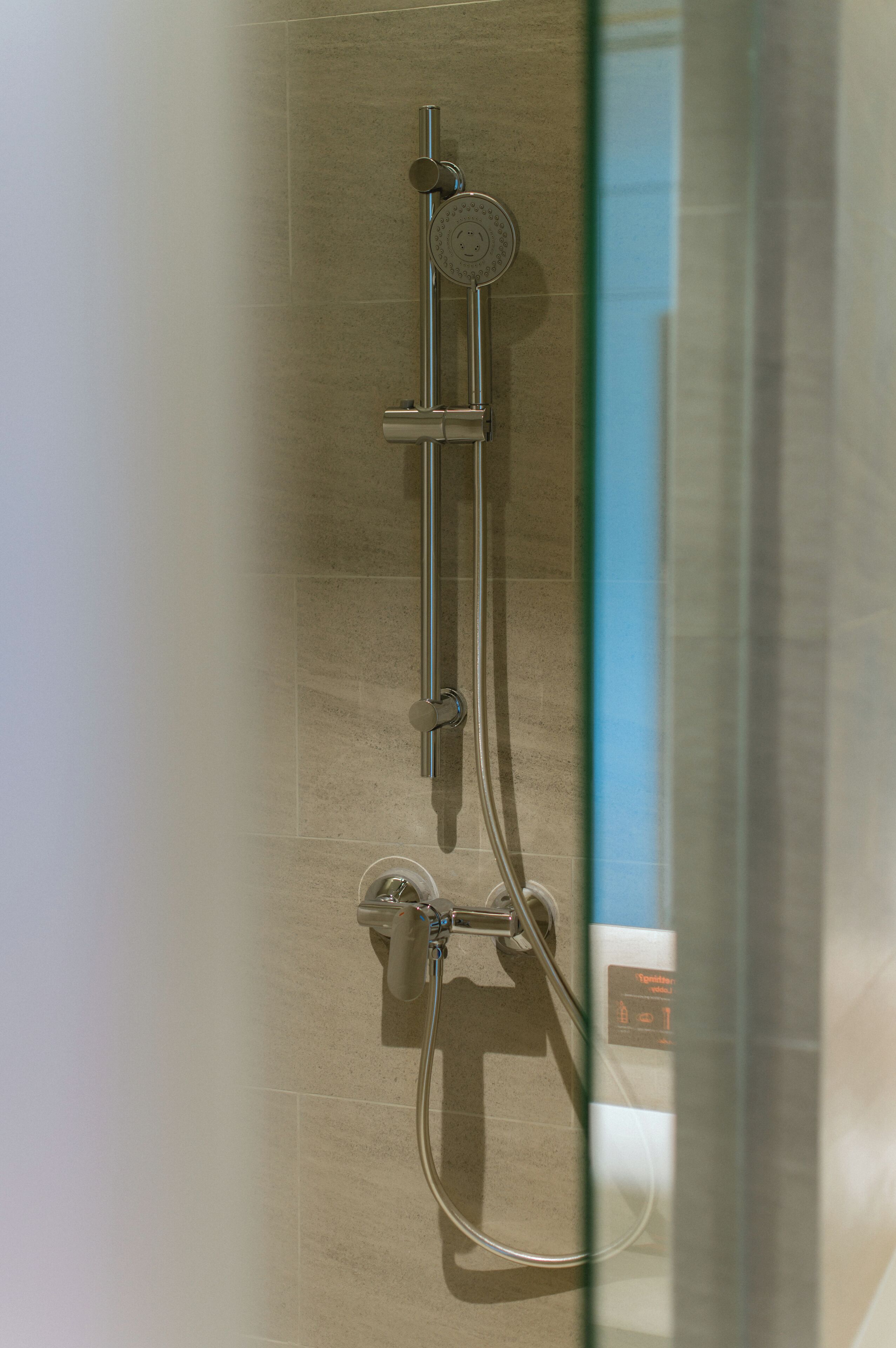 A shower with a handheld showerhead and a wall-mounted control panel.