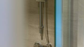 A shower with a handheld showerhead and a wall-mounted control panel.