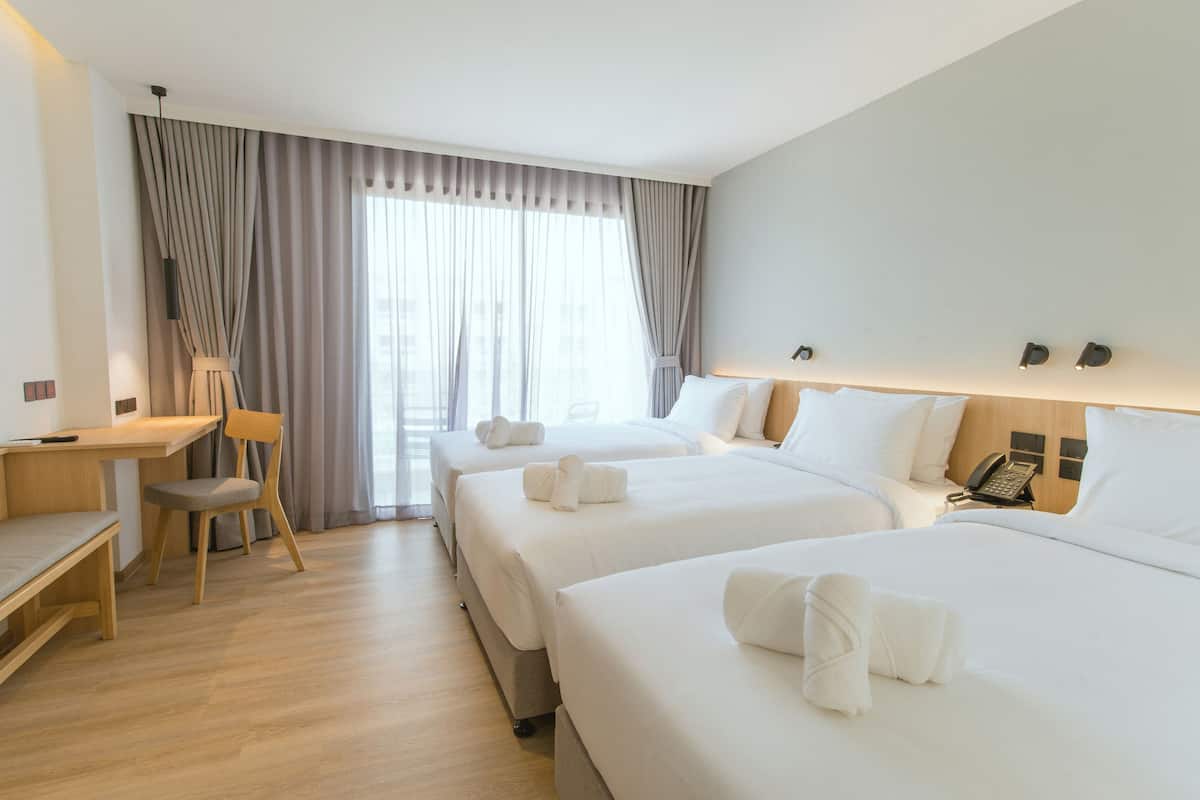 A hotel room with two beds, a desk, a chair, and a window with curtains.