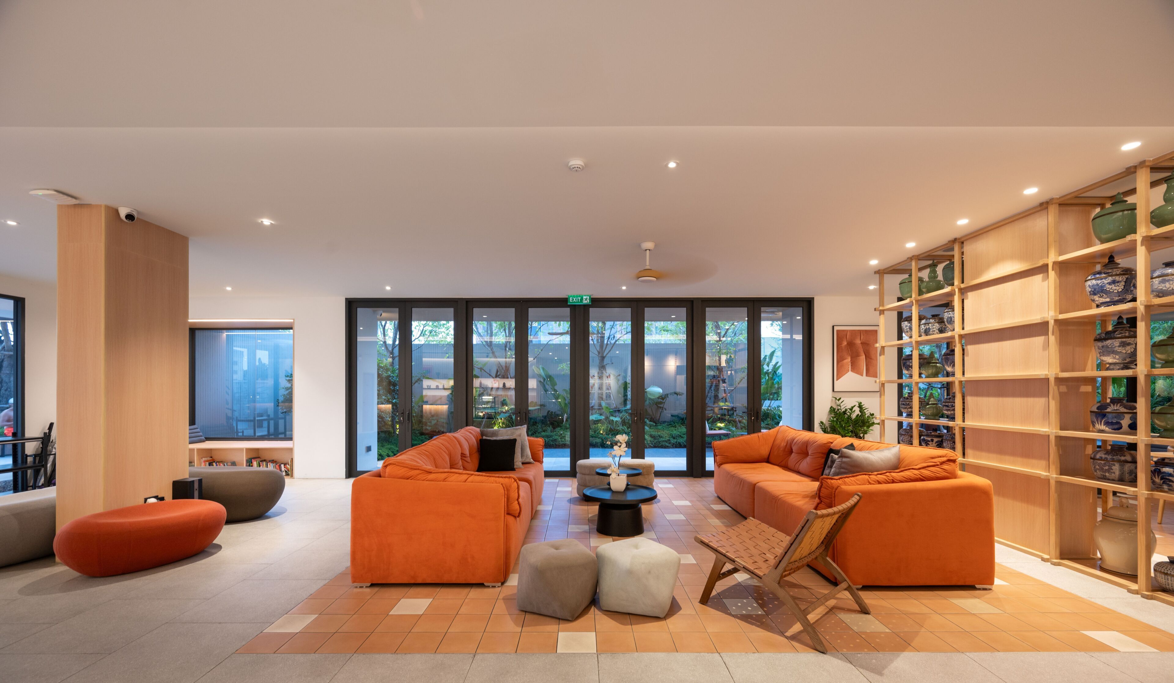 A spacious lobby with orange sofas, a coffee table, and a bookshelf filled with decorative items.