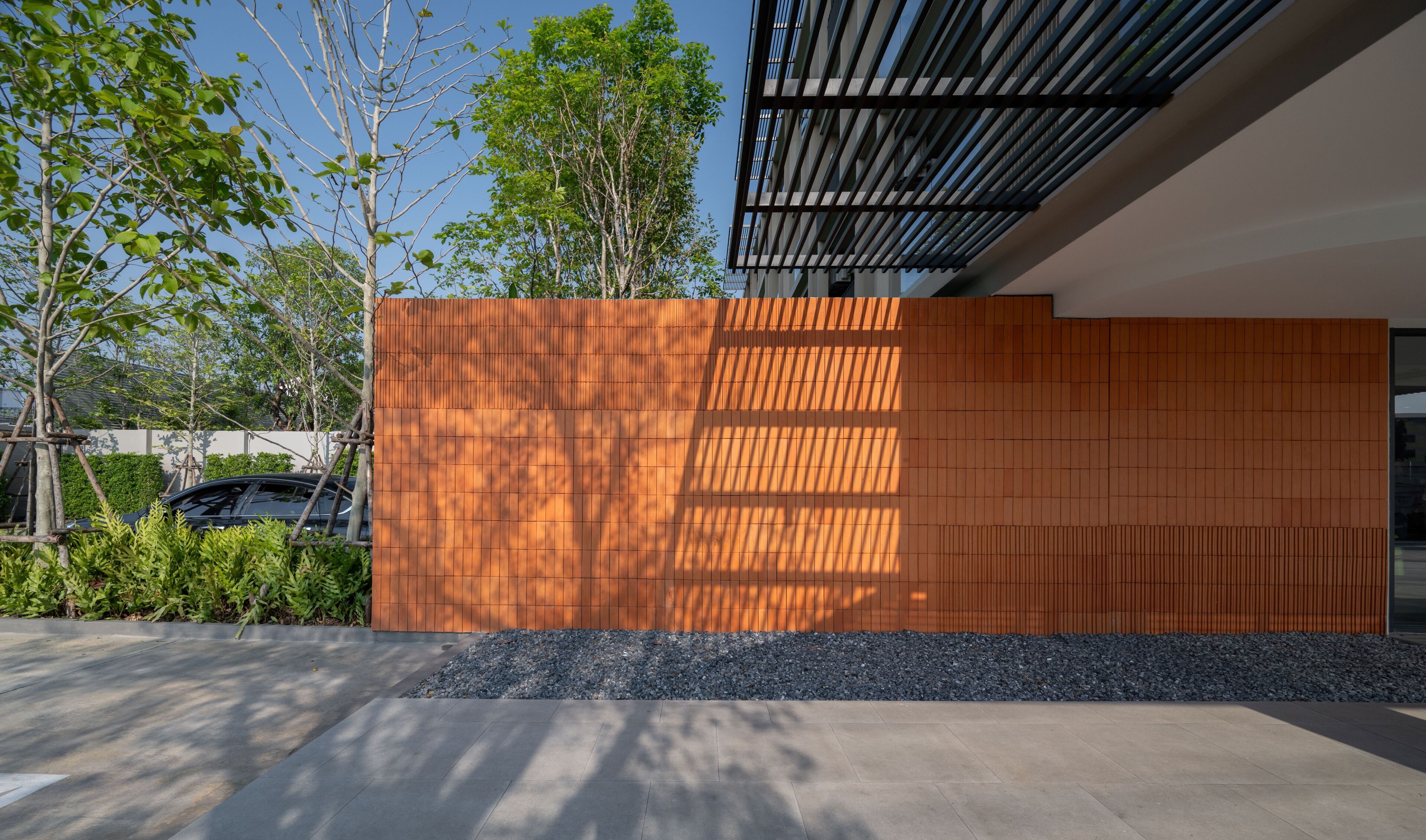 A modern building with a wooden panel facade, a concrete ground, and a clear sky.