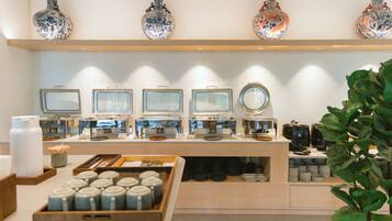 A buffet setup with multiple serving stations, a variety of dishes, and decorative vases on the wall.