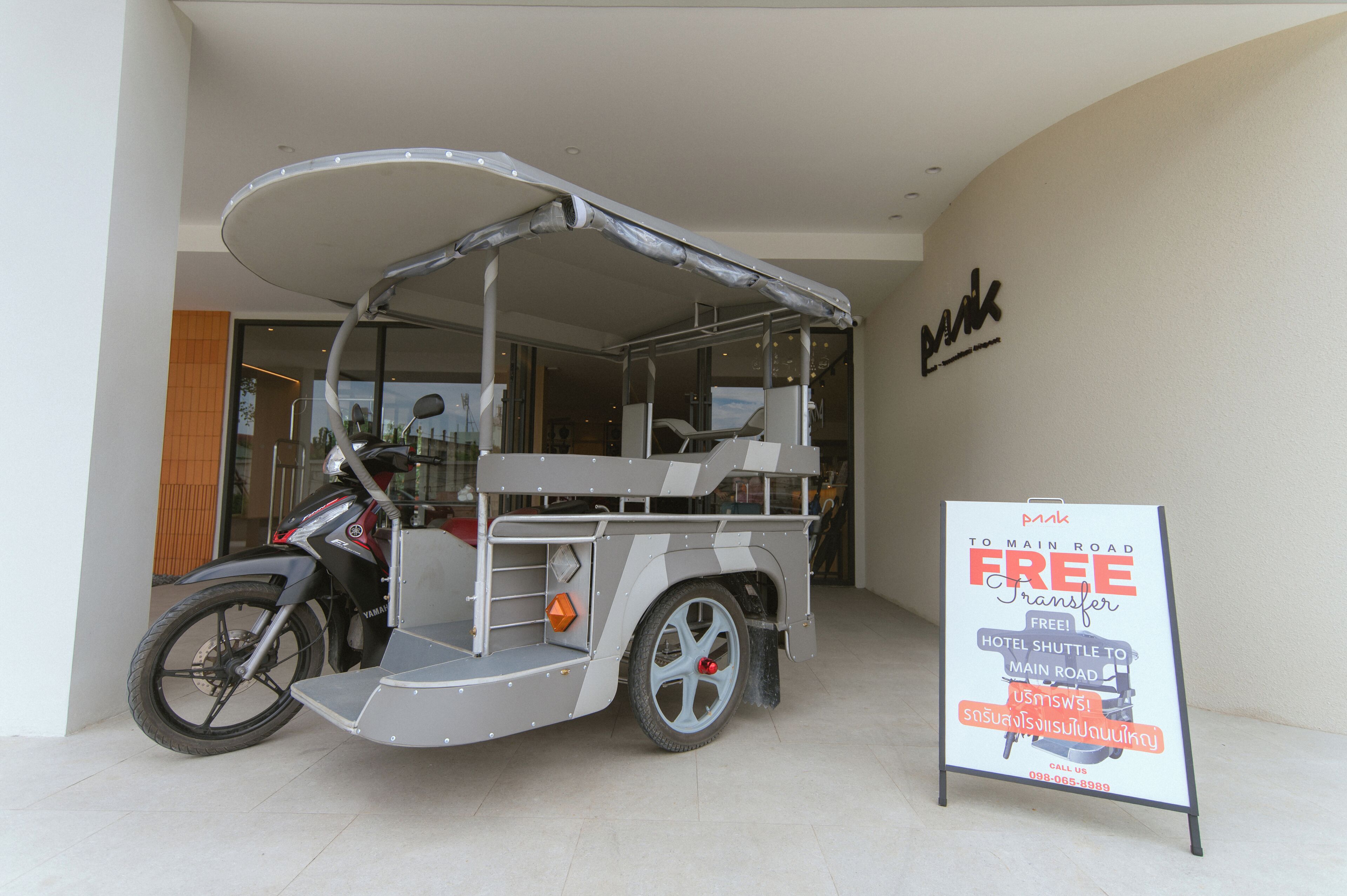 A motorcycle parked next to a signboard advertising a free hotel shuttle service.