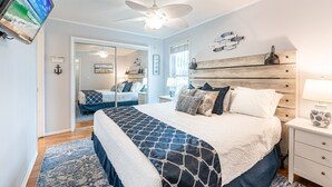 A bedroom with a large bed, a ceiling fan, a TV, and a wooden headboard. - Welcome to Kitzi’s Corner – Pet-Friendly 1BR Retreat with FREE Beach Service! (Destin)