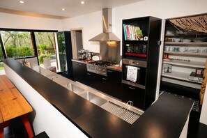 A modern kitchen with a central island, stainless steel appliances, and a built-in bookshelf.
