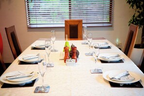 A dining table set for four with plates, cutlery, and glasses.
