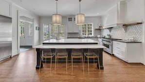 A spacious kitchen with a large island, white cabinetry, and a patterned backsplash. - Luxury 5BR Buckhead Home | World Cup Ready (Atlanta)