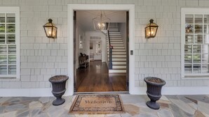 A house entrance with a wooden staircase, two wall-mounted lanterns, and a welcome mat. - Luxury 5BR Buckhead Home | World Cup Ready (Atlanta)