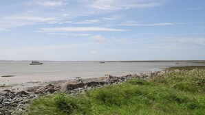 Un paisaje costero con playa arenosa, costa rocosa y mar tranquilo.