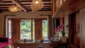 A wooden interior with a dining table, two hanging wicker lamps, and a view of a lush garden through open doors. - Yama VIlla & SPA Ubud (Payangan)
