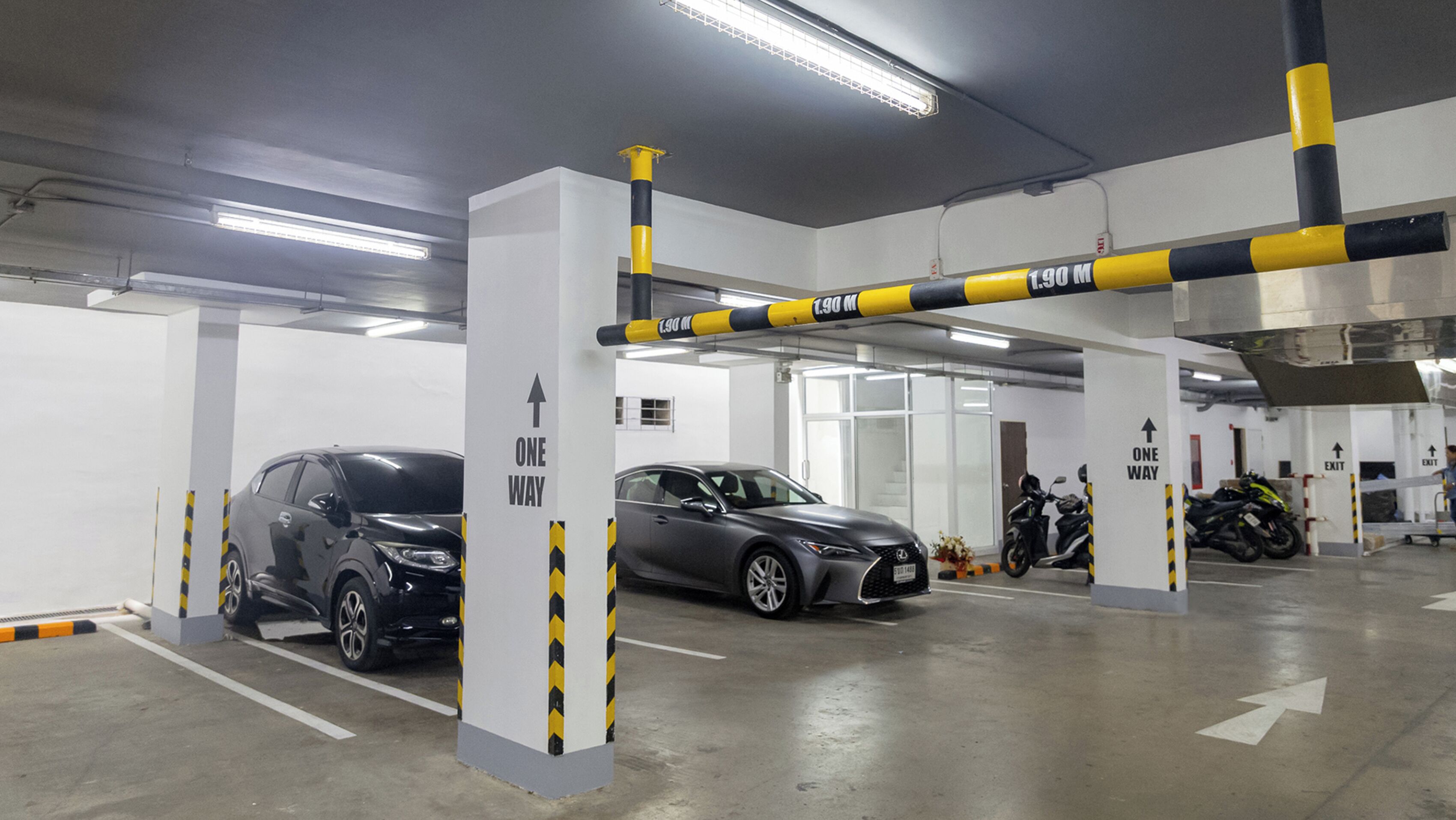 A parking garage with marked one-way traffic lanes, a motorcycle, and a car.