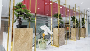 Een moderne ruimte met potplanten, marmeren vloeren en een rood plafond.