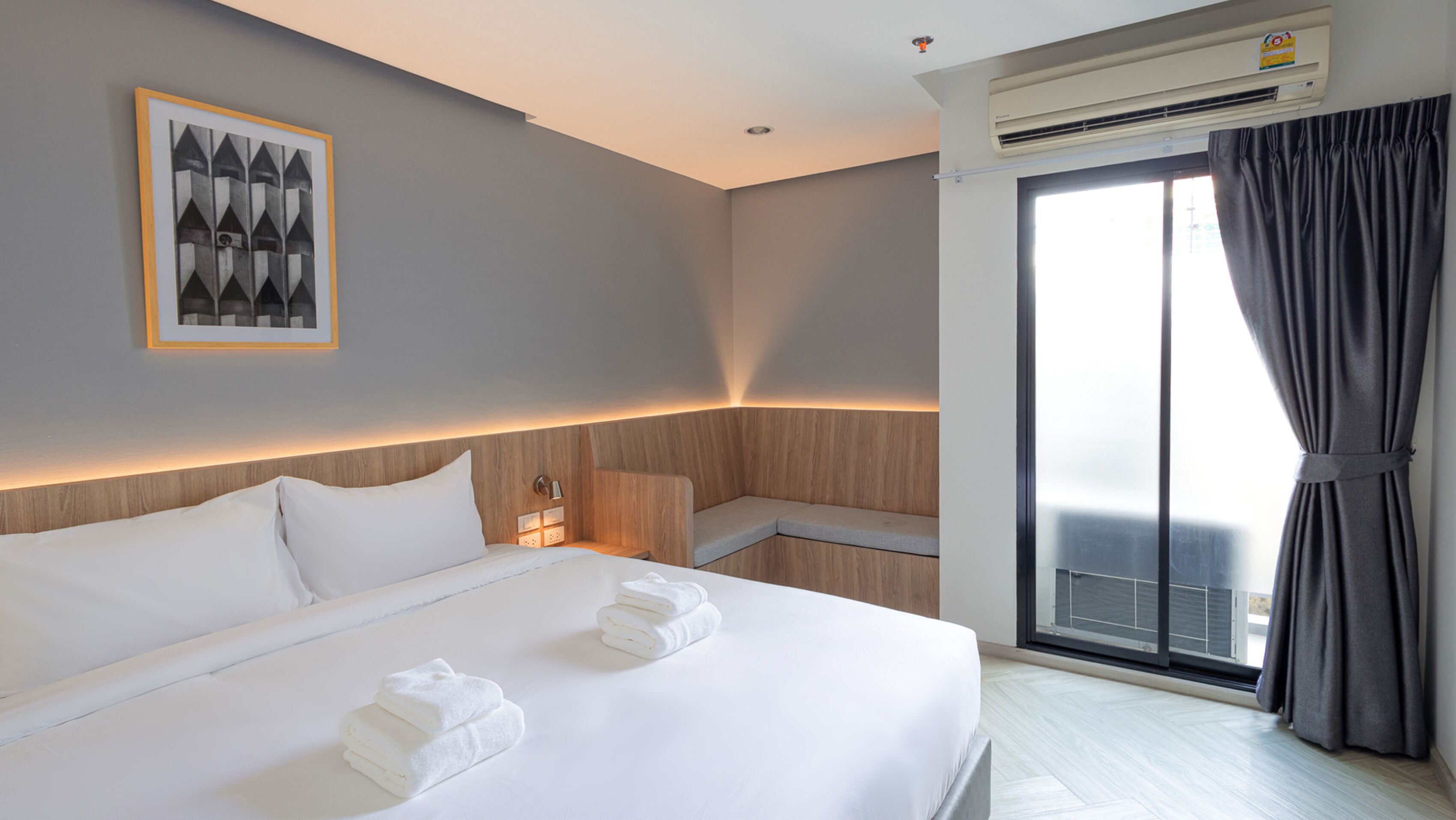 Una camera d'albergo moderna con un letto grande, un'area salotto e vista all'esterno.