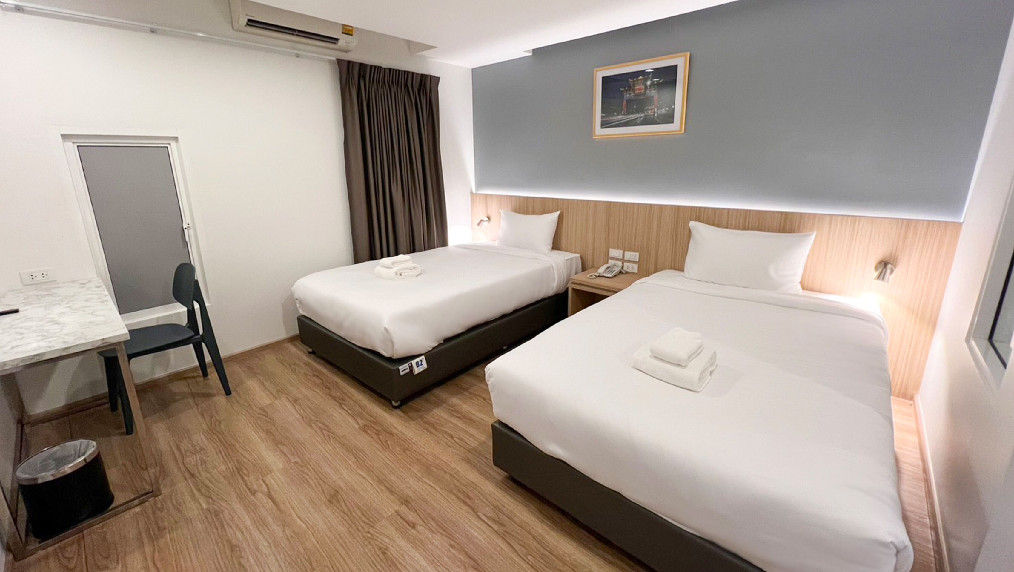 Une chambre d’hôtel avec deux lits, un bureau, une chaise, un téléphone et un appareil de climatisation.