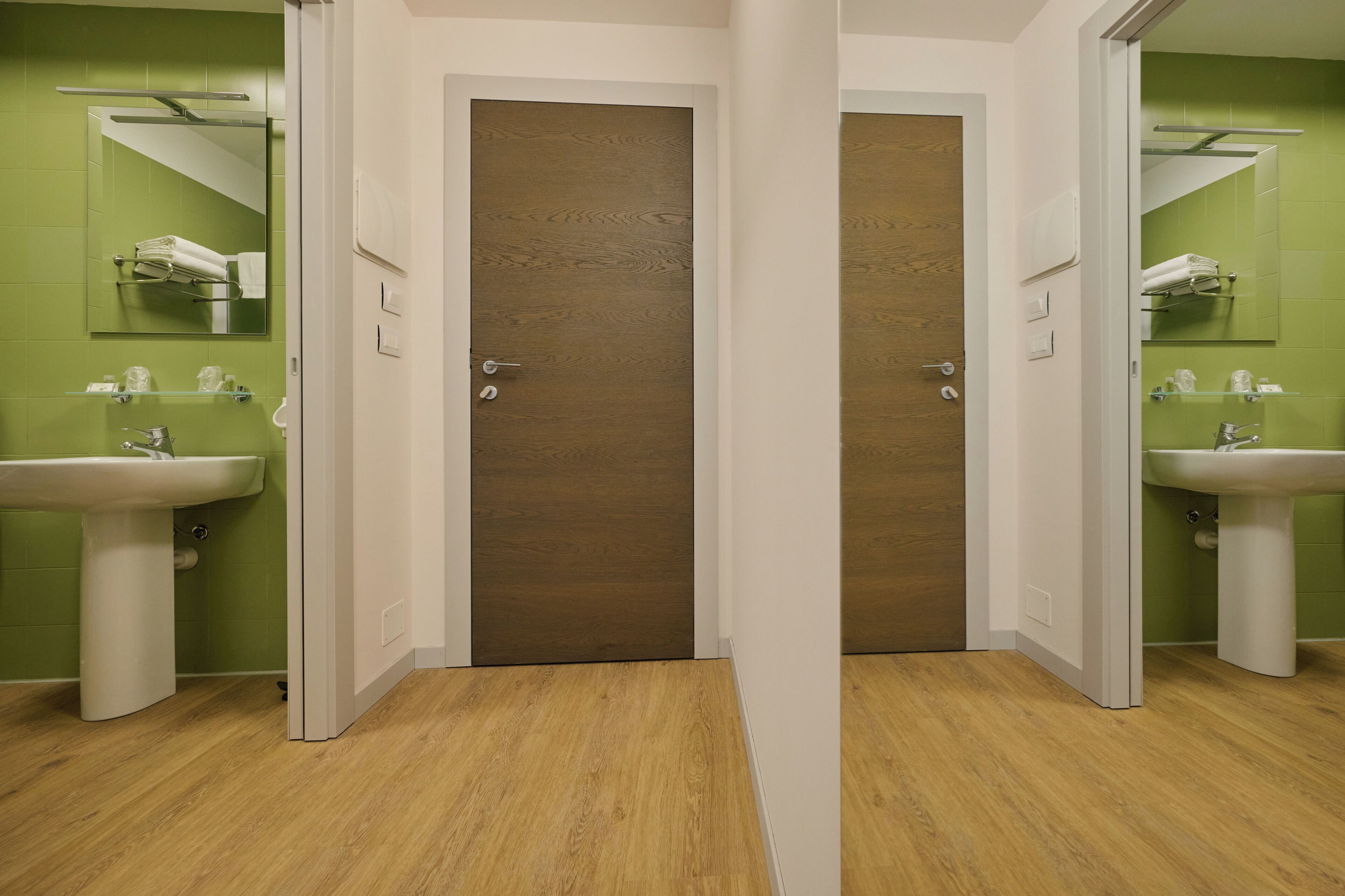 A bathroom with two sinks, green walls, and a wooden door.