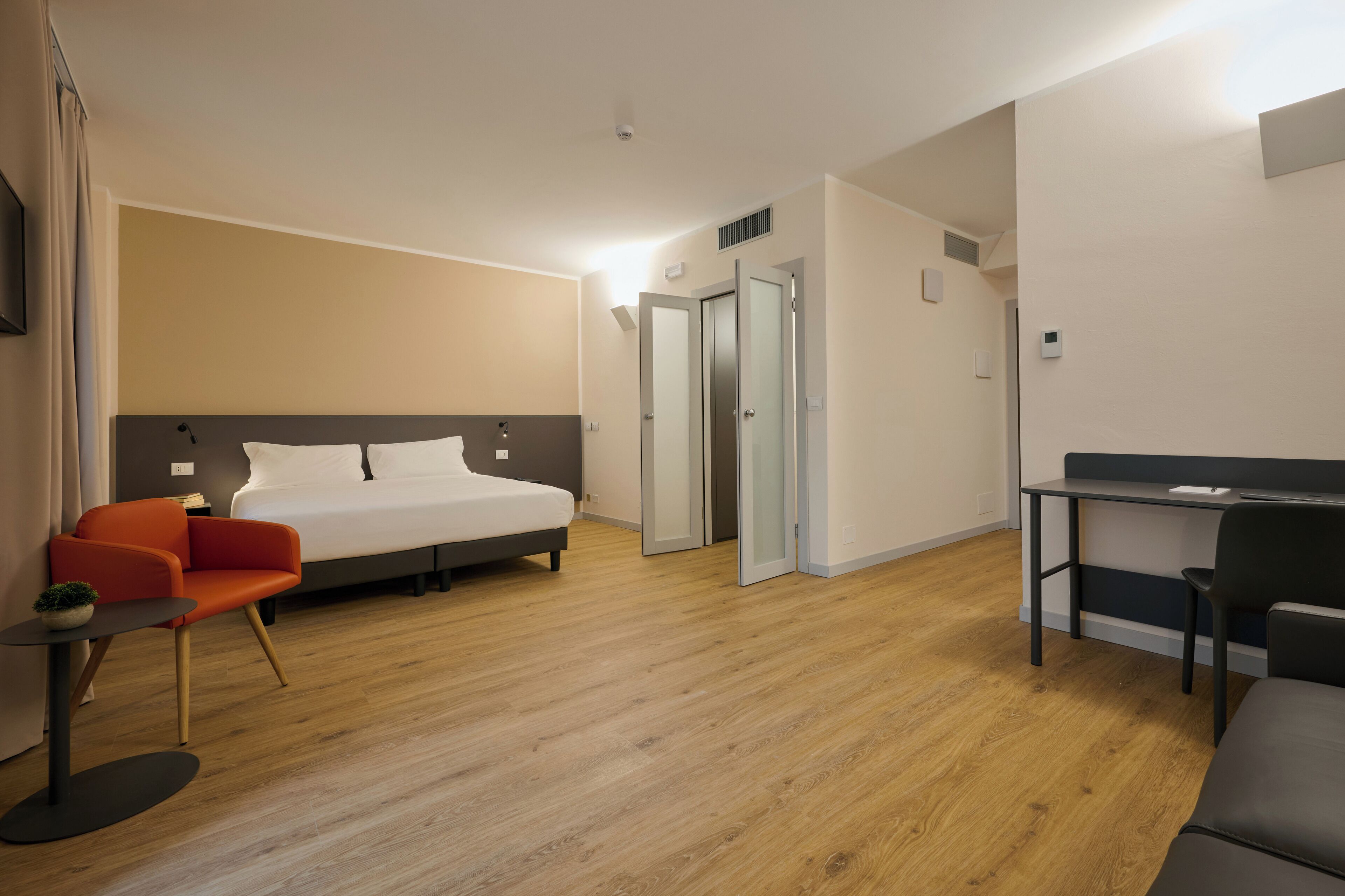Una habitación de hotel moderna con cama, escritorio, silla y una pequeña mesa.