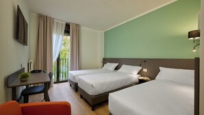 A hotel room with two beds, a desk with a chair, a small table with a plant, and a view of the outdoors. - Zenit Park Hotel (Rivalta di Torino)