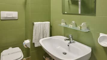 A bathroom with green walls, a white sink, a toilet, a mirror, and a towel rack.