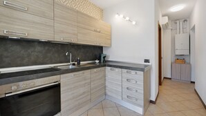 A modern kitchen with built-in appliances, a patterned backsplash, and a light fixture above the countertop.