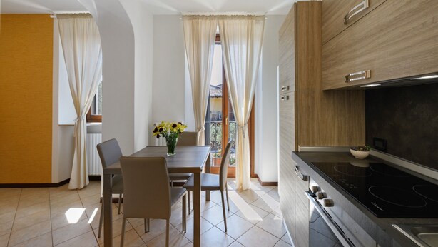 A modern kitchen with a dining area, a view to the outside, and a wooden cabinet with a microwave.