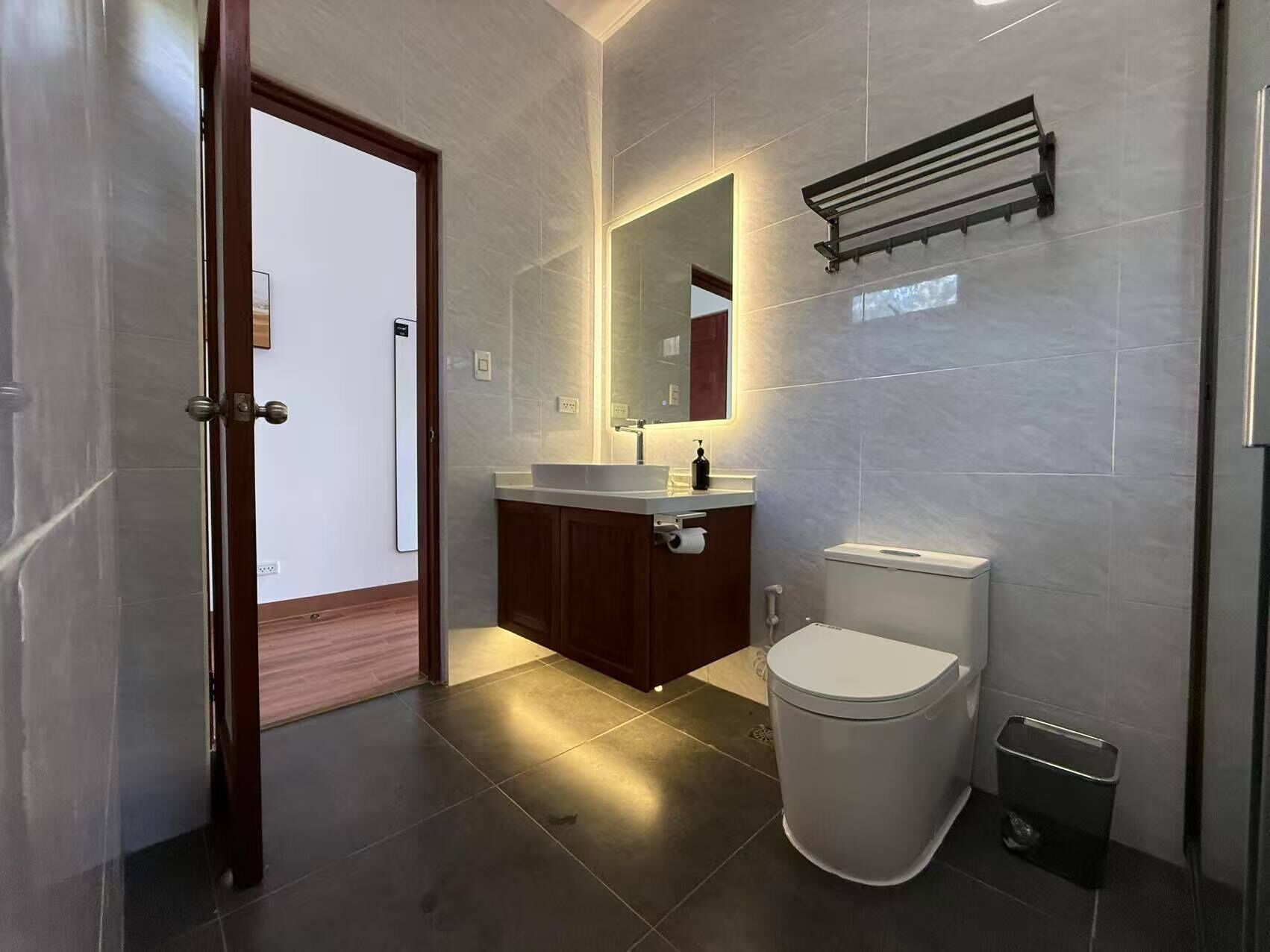 Un baño moderno con inodoro, lavabo y espejo.