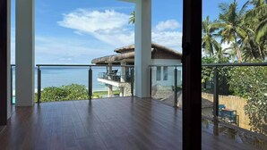 A spacious balcony with a view of the ocean and palm trees.
