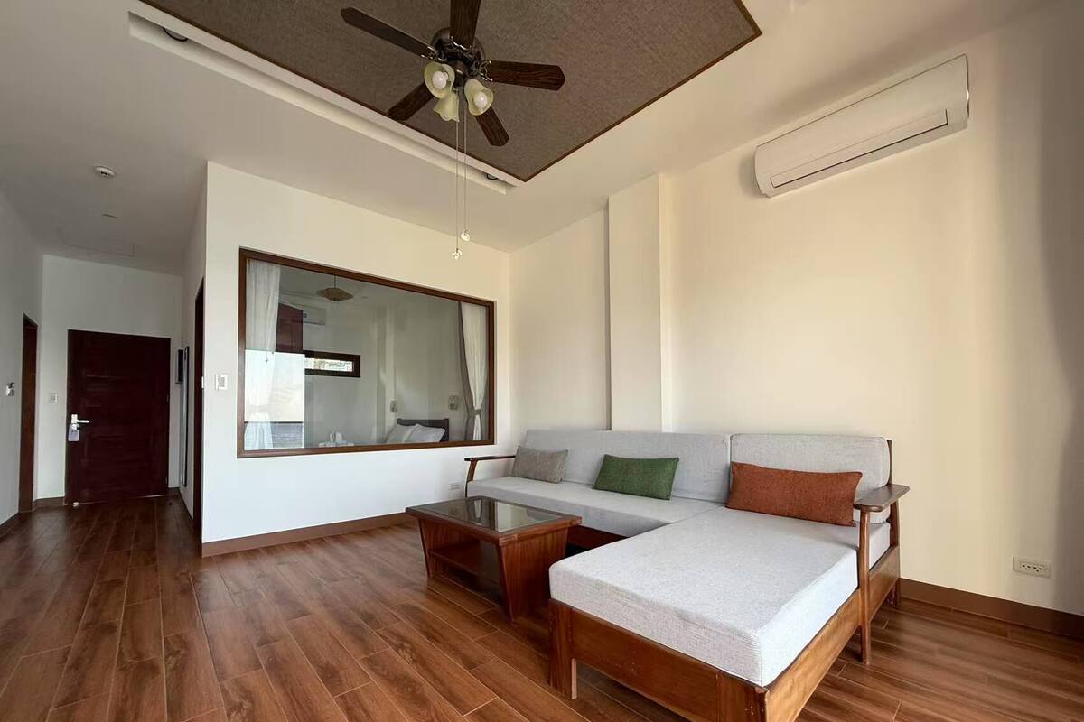 A spacious living area with a wooden floor, a sofa, a coffee table, and a ceiling fan.