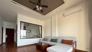 A spacious living area with a wooden floor, a sofa, a coffee table, and a ceiling fan.