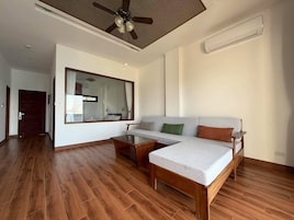 Un salón amplio con piso de madera, un sofá, una mesa de centro y un ventilador de techo.