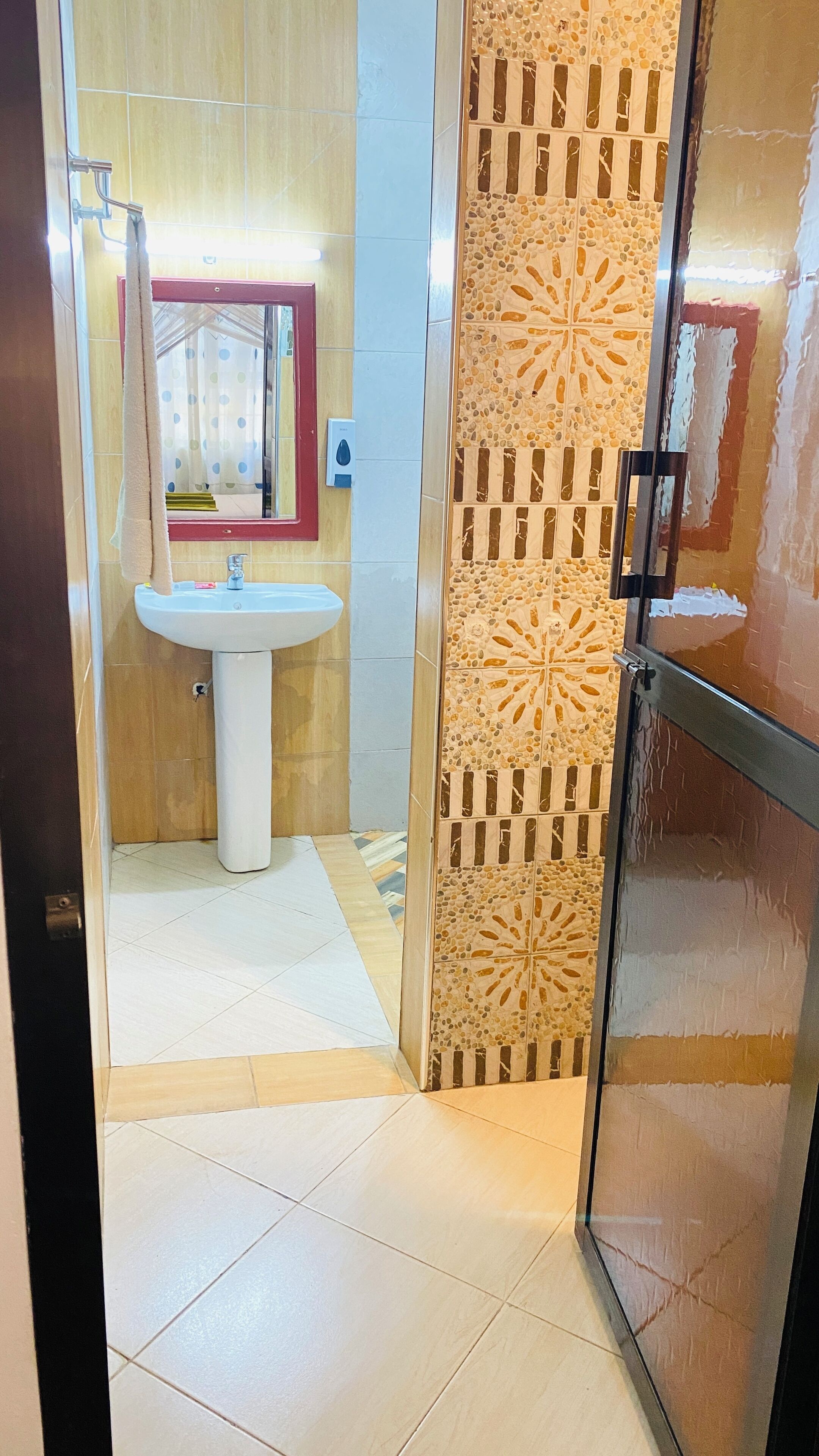 A bathroom with a glass shower enclosure, a sink, and a mirror.
