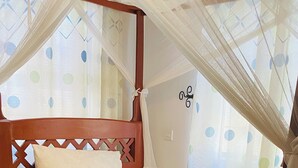 A bed with a wooden frame, white bedding, and a yellow pillow. - parachichi house Bed and Breakfast  (Arusha)