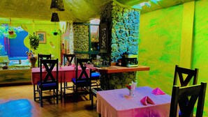 A restaurant with stone walls, wooden tables, and chairs. - parachichi house Bed and Breakfast  (Arusha)