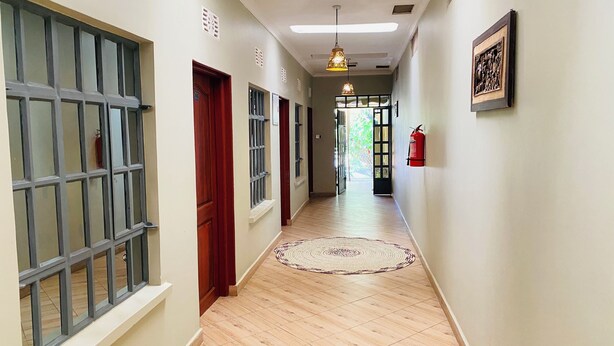 A hallway with wooden flooring, a patterned rug, and a fire extinguisher on the wall. - parachichi house Bed and Breakfast  (Arusha)