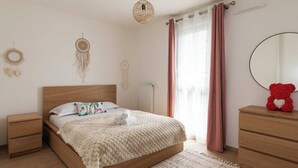 Een slaapkamer met een houten bed, nachtkastjes, een spiegel, een rood teddybeer en decoratieve wanddecoraties.